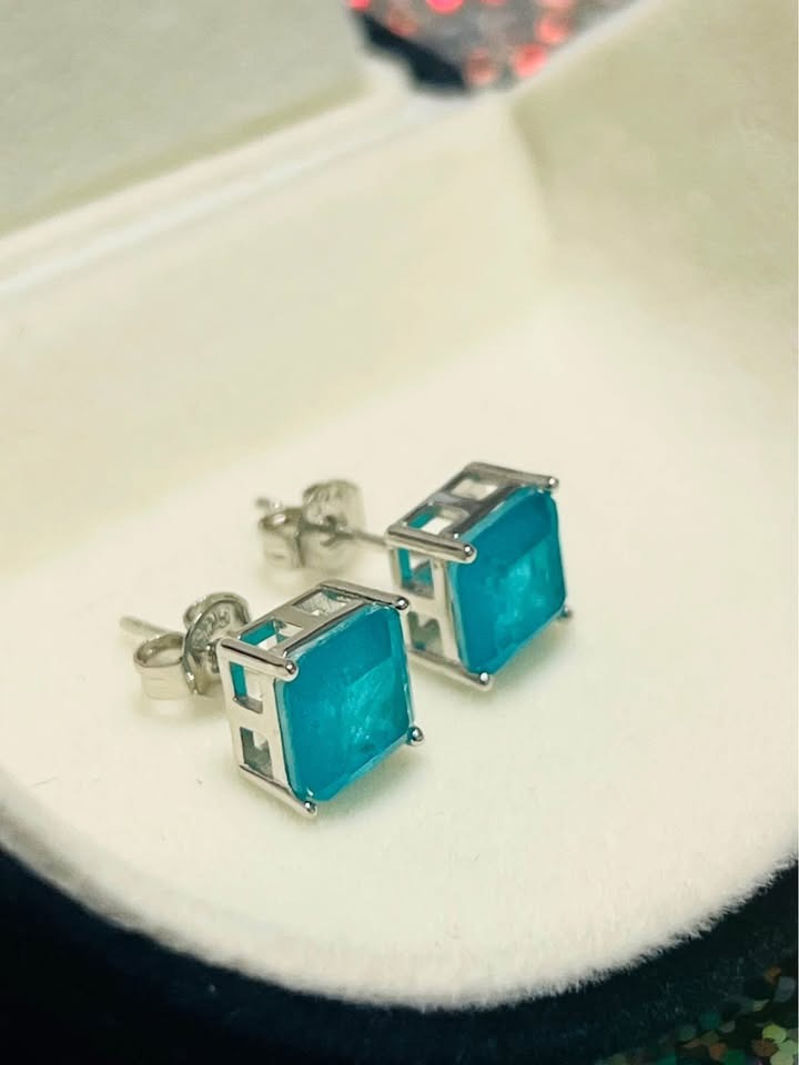 Side view of dainty genuine blue topaz square stud earrings set in sterling silver, showing their sturdy prong setting.