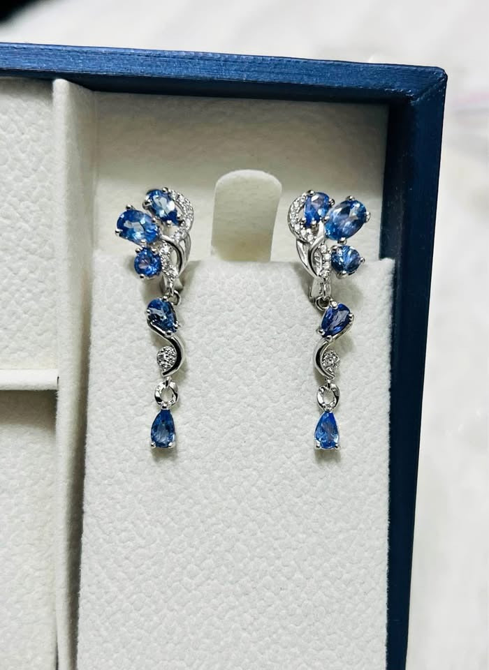  A pair of natural blue tanzanite teardrop earrings showcased in a jewelry box.