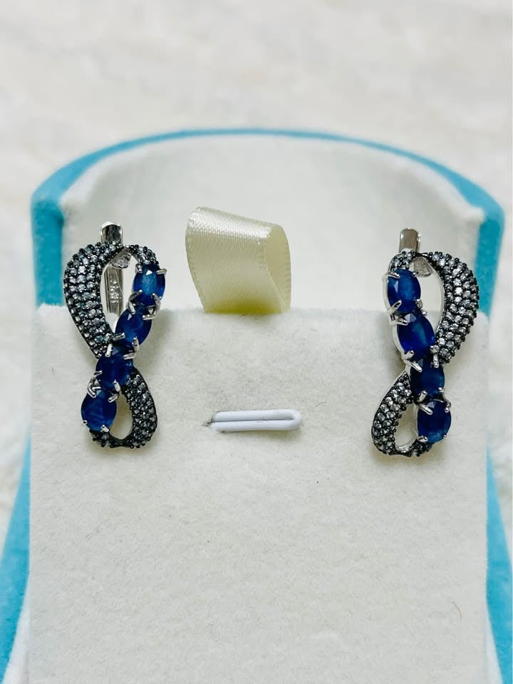 Elegant blue sapphire infinity drop earrings with sparkling accents.
