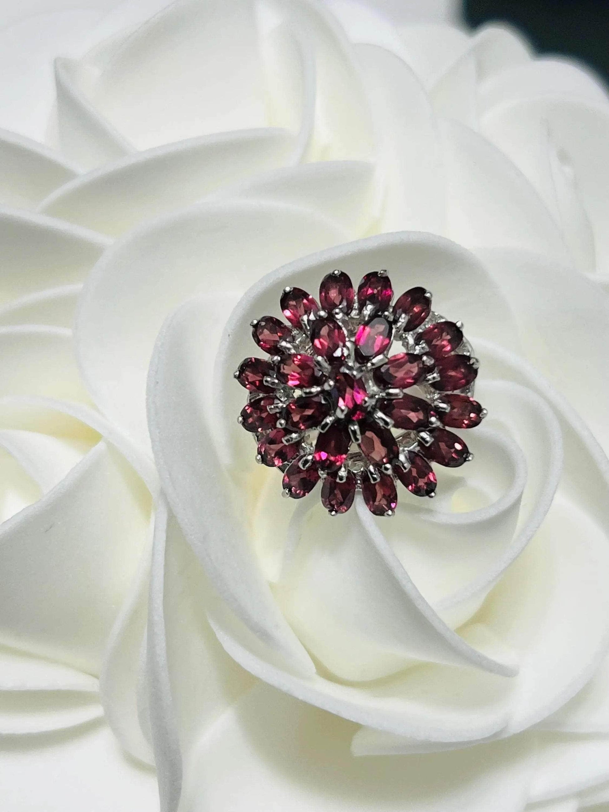 Exquisite Bochic vintage rhodolite garnet floral ring on a soft white rose, showcasing its deep red hues.