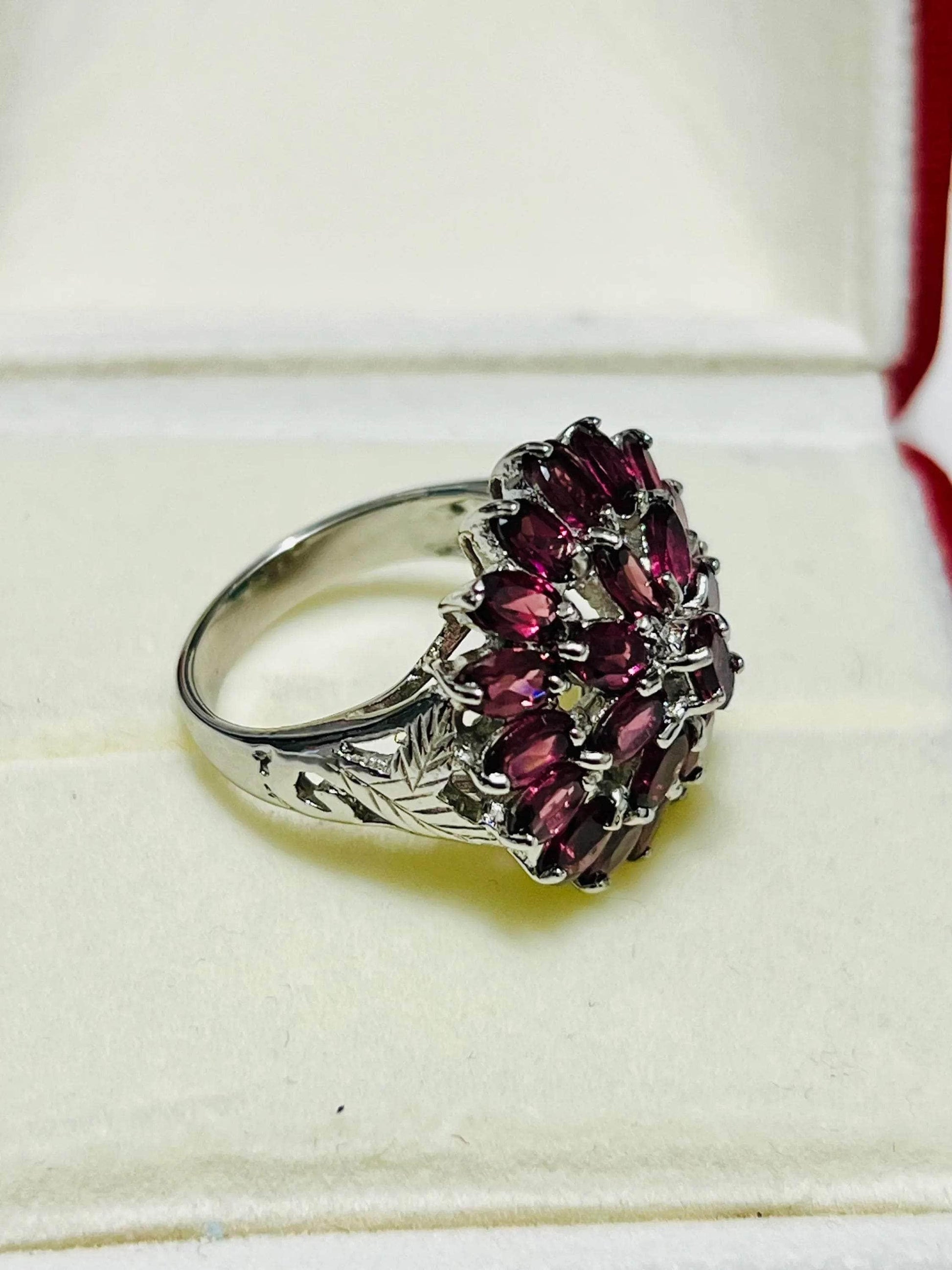 Side view of a Bochic vintage rhodolite garnet ring in a display box, revealing intricate band engravings.
