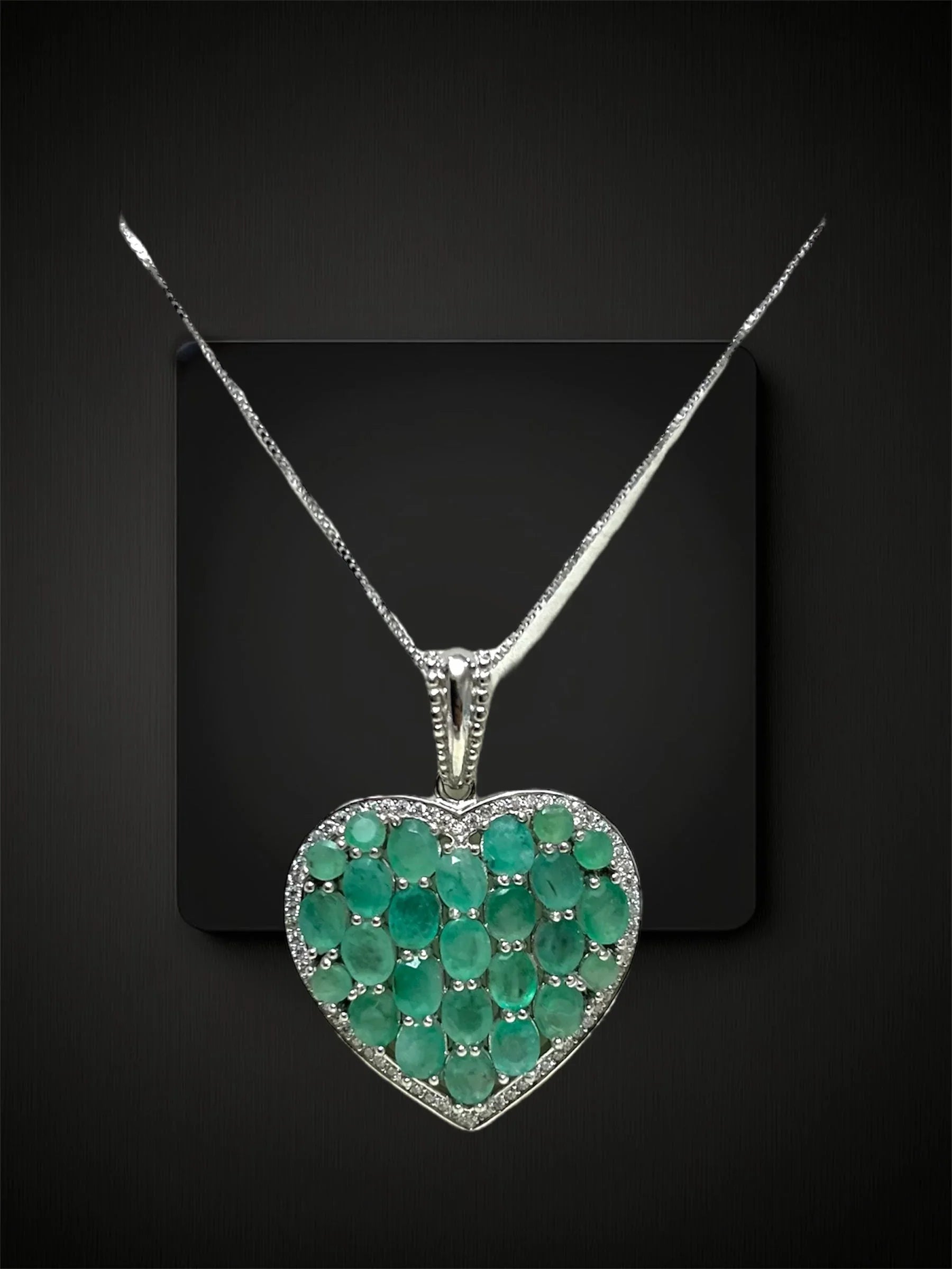 Breathtaking heart-shaped sterling silver pendant with 7ct Colombian emeralds & diamonds, on black.