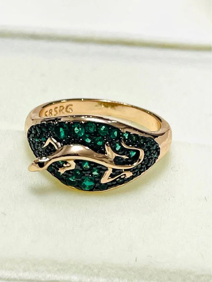 Close-up of a 585RG stamped rolled gold salamander ring with intricate green emerald detailing.