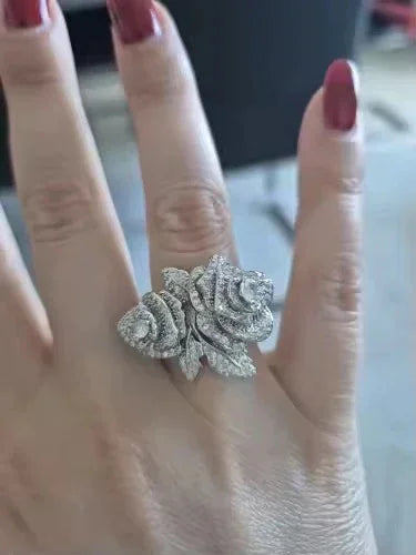 Close-up of a hand with red nails, featuring a sparkling rose-shaped gold vermeil CZ statement ring.