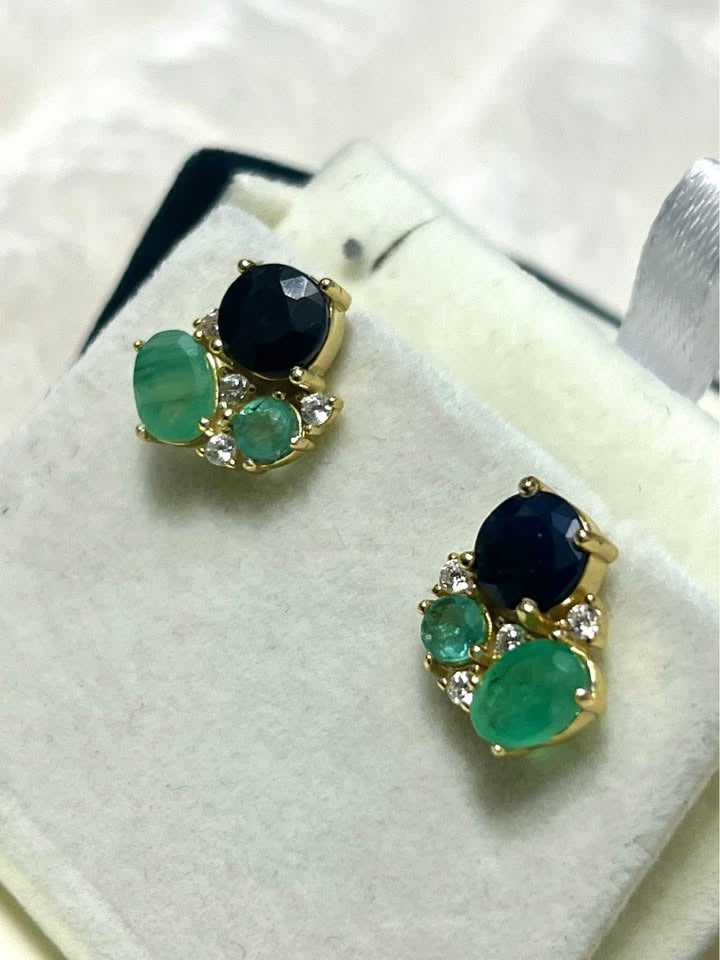 Close-up of Colombian emerald and sapphire cluster stud earrings in a jewelry box.