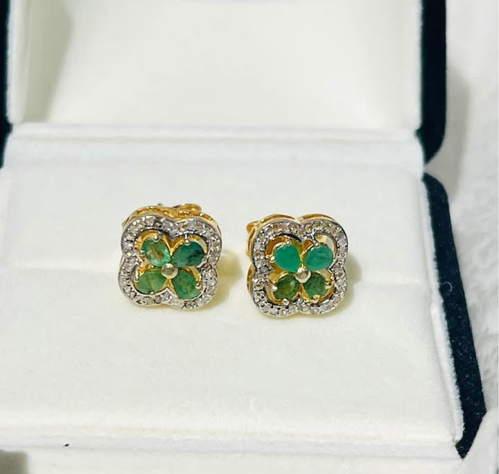 Close-up of Colombian emerald and diamond flower earrings, capturing their brilliance and setting within a box.