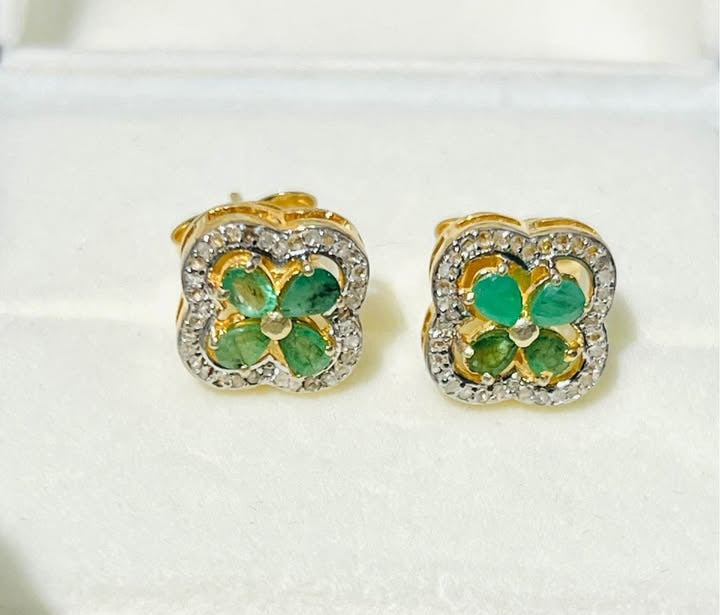 Exquisite Colombian emerald and diamond flower-shaped stud earrings in a white jewelry box.