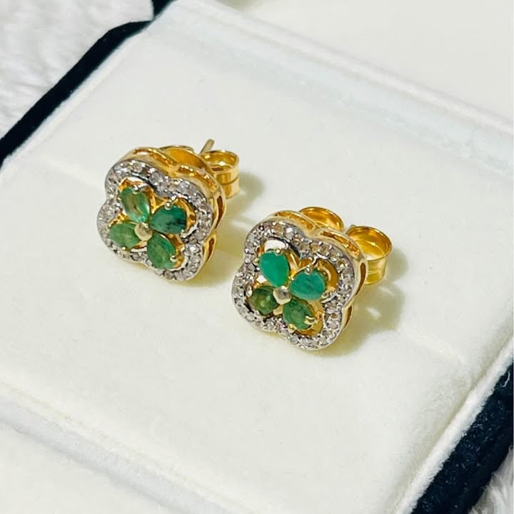 Angled view of elegant Colombian emerald and diamond stud earrings, showcasing their intricate design.