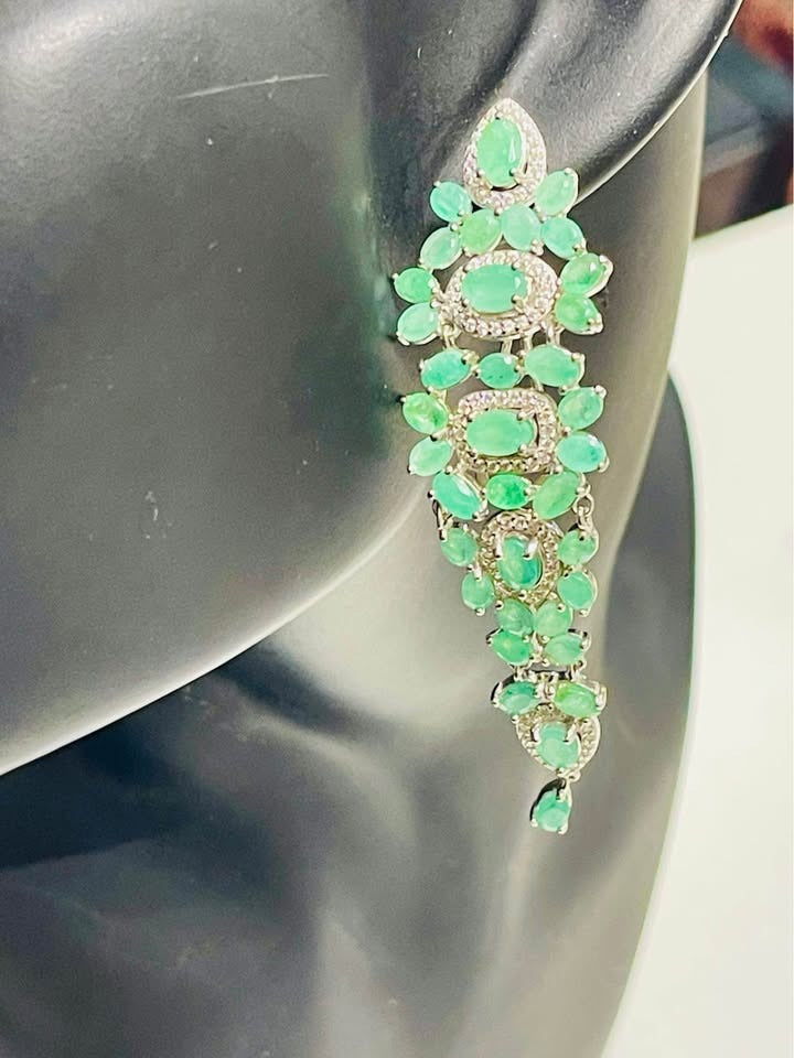 Stunning drop earrings with natural Colombian emeralds and cubic zirconia, on a black jewelry bust.