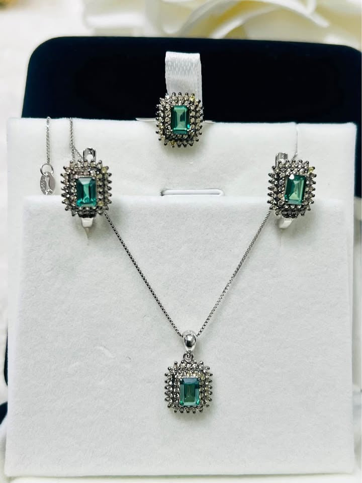 A complete set of green tourmaline and diamond jewelry, featuring a ring, earrings, and a pendant, displayed.