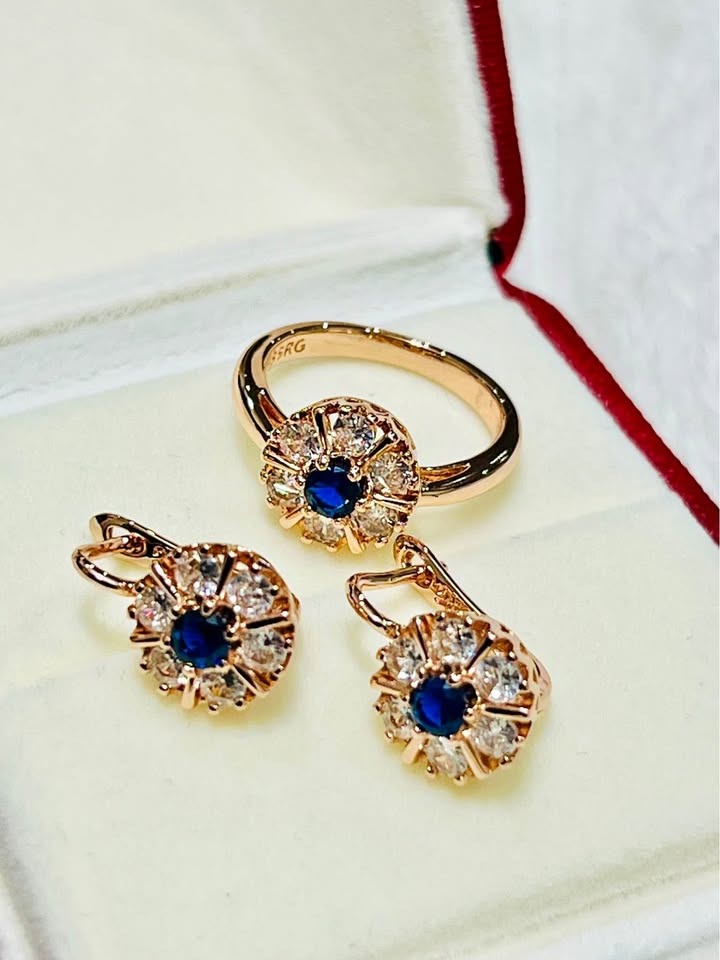 Luxurious rose gold jewelry set showcasing a floral motif with a central blue sapphire and shimmering diamond accents.