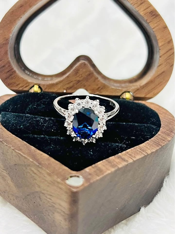 Diana-inspired sapphire ring with a halo of sparkling stones, perfectly centered in a heart-shaped box.