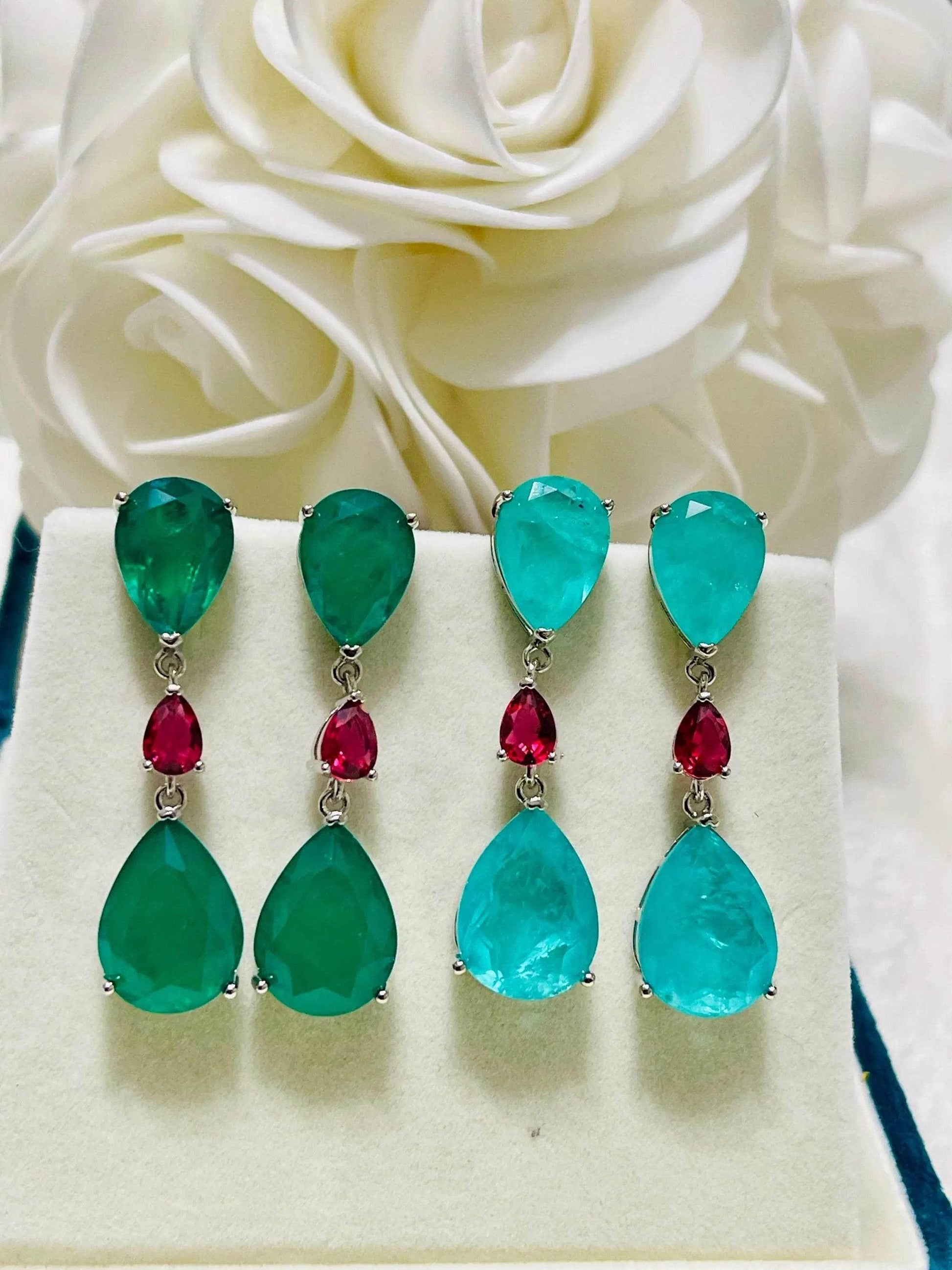 Set of vibrant green emerald and striking blue-green Paraiba doublet drop earrings with red stones.