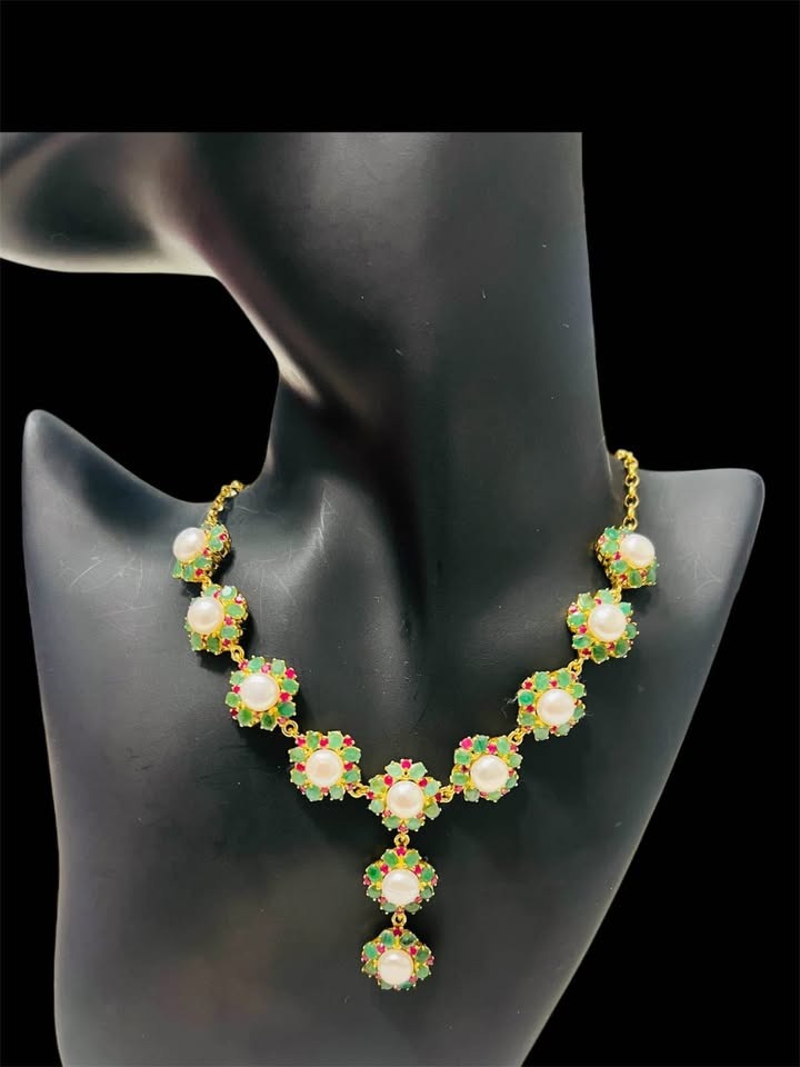 Elegant South Sea pearl necklace with natural Colombian emeralds and rubies, showcased on a mannequin.
