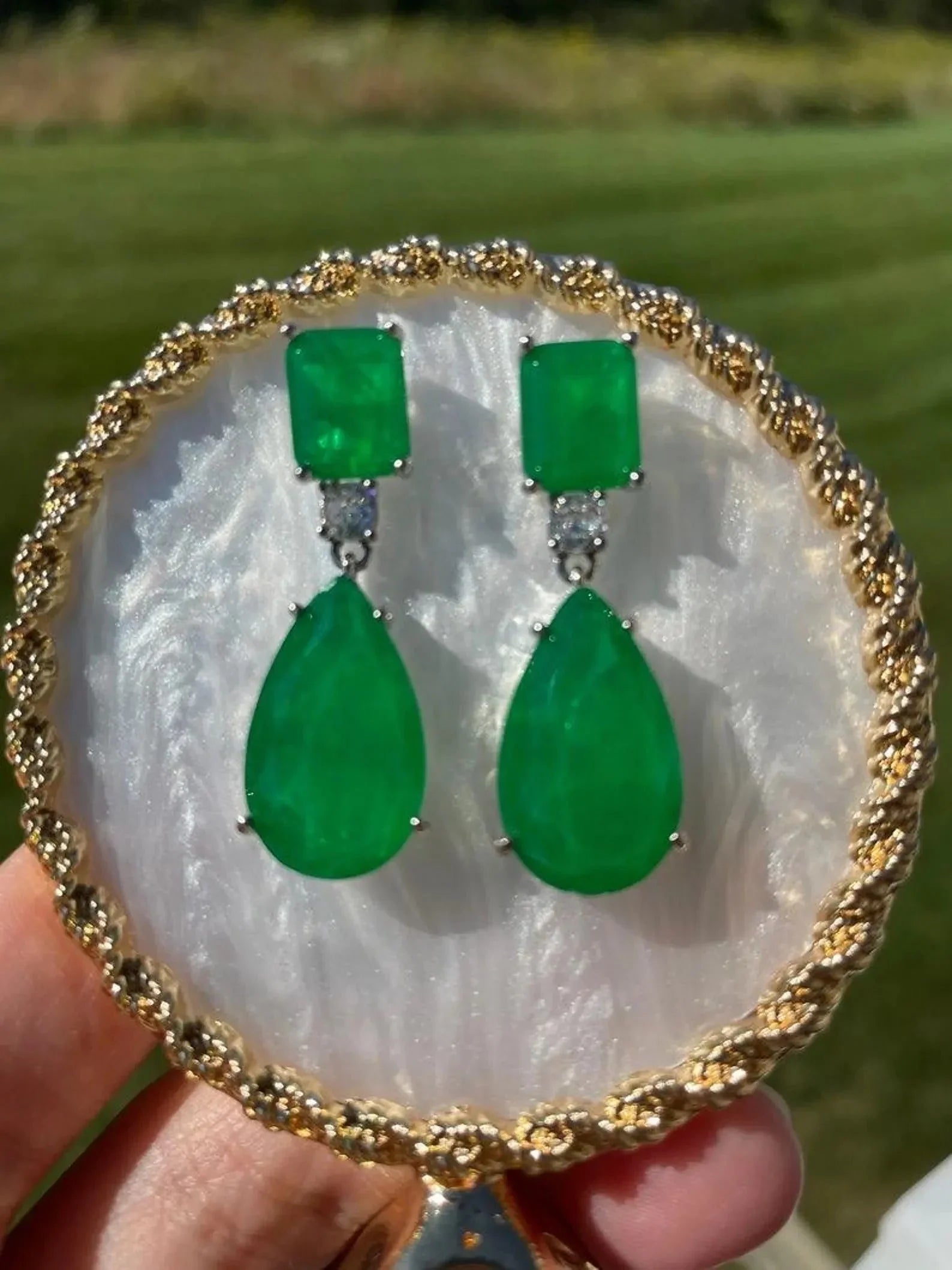 Close-up of exquisite emerald doublet earrings in 14K gold, beautifully arranged on a white and gold plate.