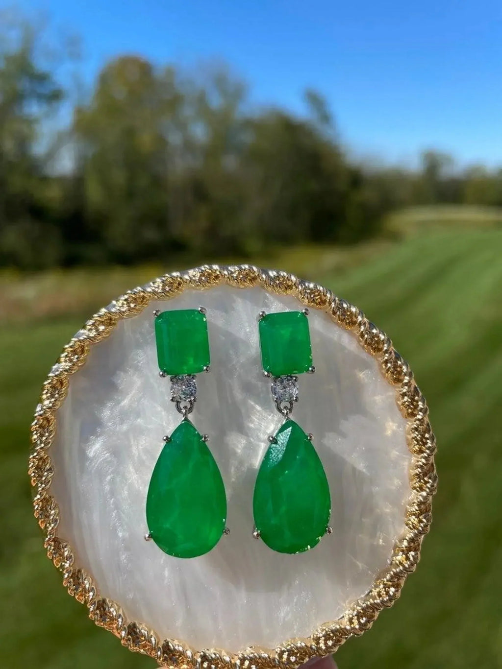 Elegant 14K gold emerald doublet earrings, beautifully presented with a clear outdoor landscape background.