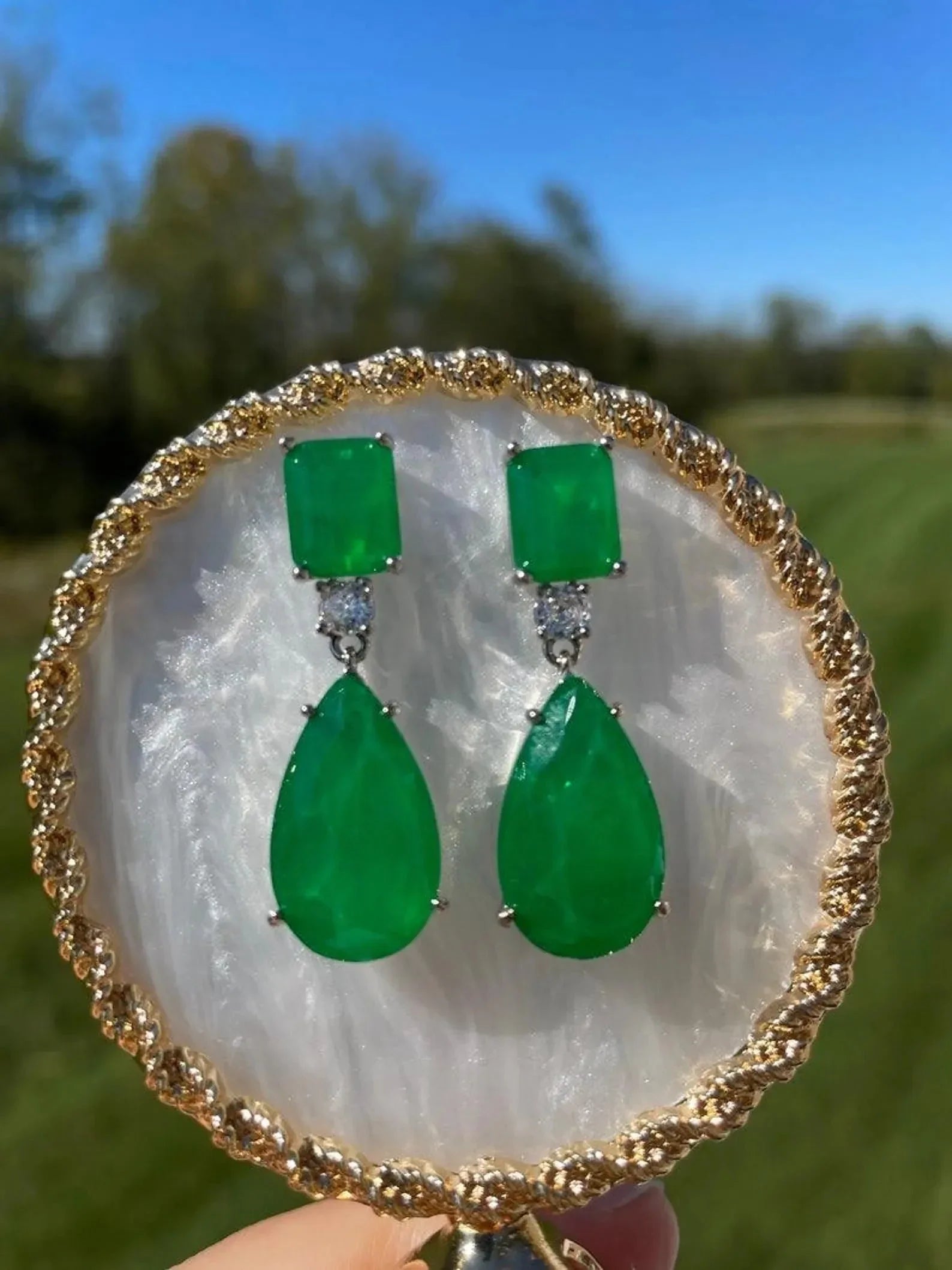 Stunning emerald doublet earrings in 14K gold, showcasing their vibrant green on a decorative plate outdoors.