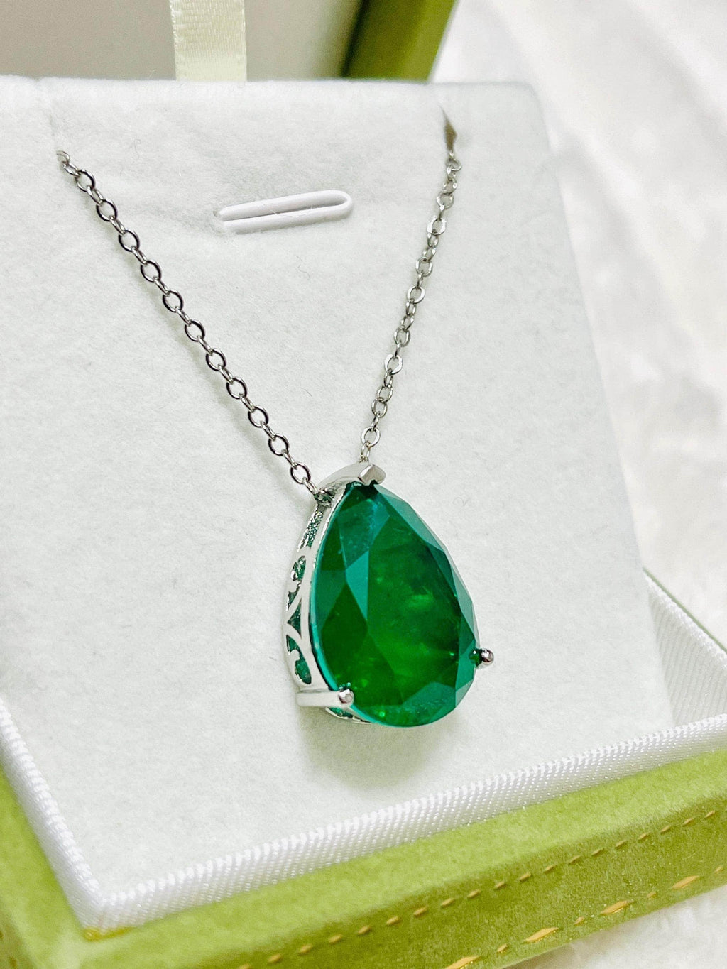 Close-up of a large Zambian emerald doublet necklace, highlighting its vibrant green color and setting.