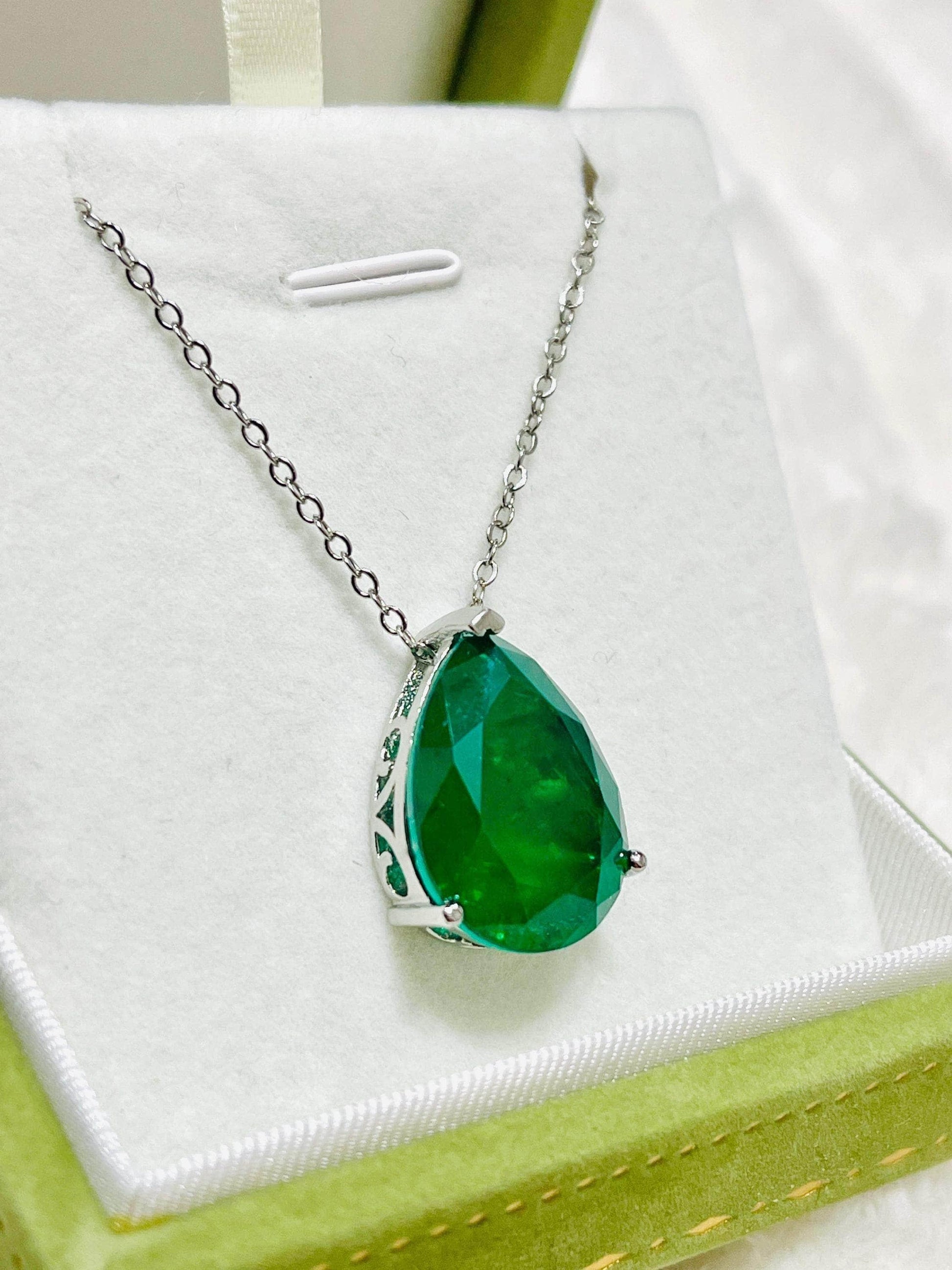 Close-up of a large Zambian emerald doublet necklace, highlighting its vibrant green color and setting.