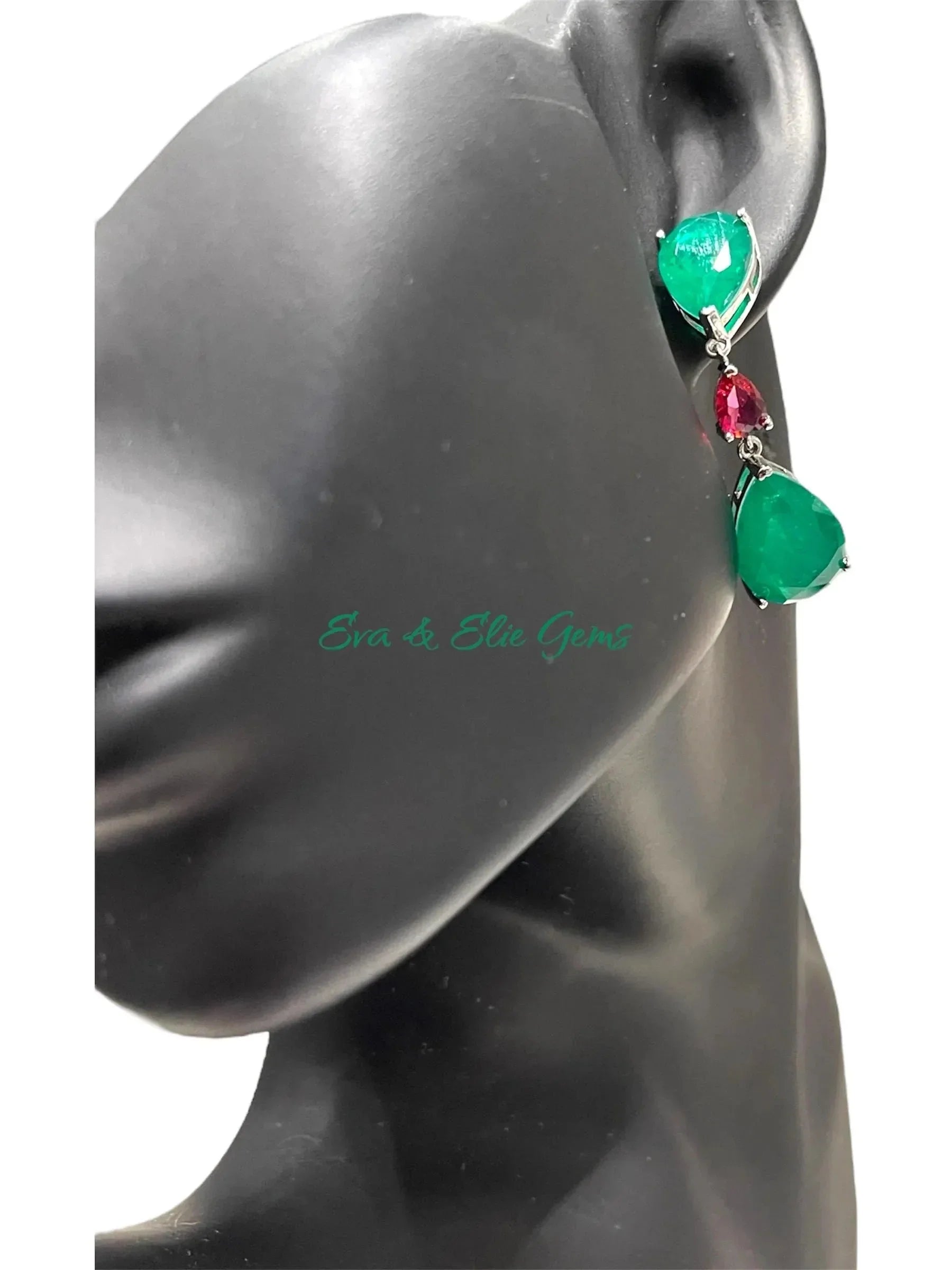 Emerald doublet drop earring with red accent stone modeled on a black mannequin ear.