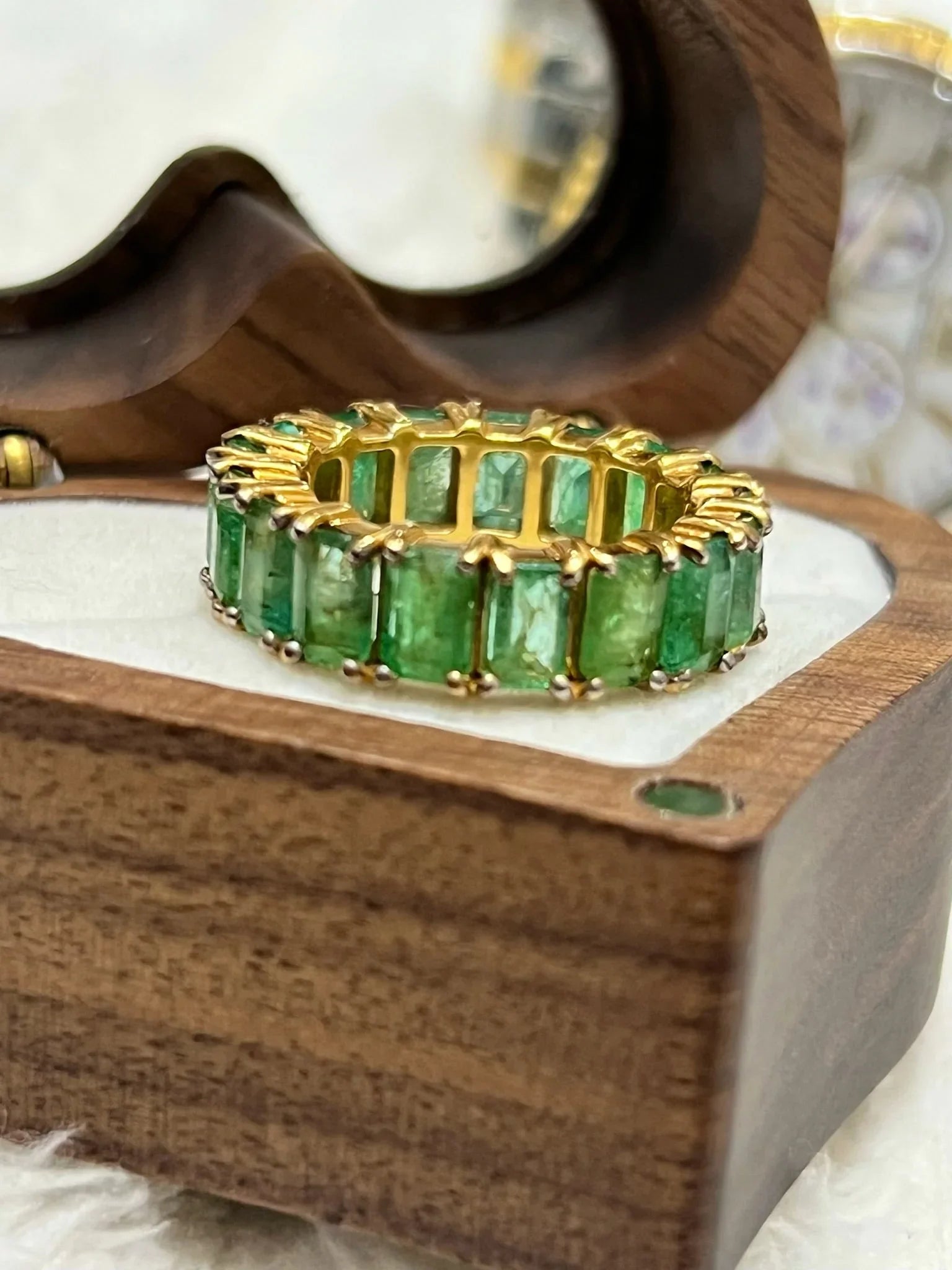 Angled view of a beautiful emerald eternity band with gold vermeil, presented in a decorative heart box.