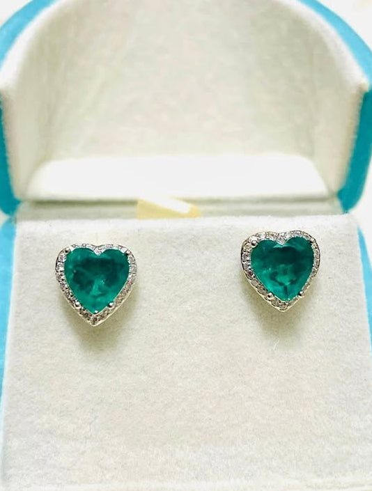  Pair of heart-shaped Zambian emerald doublet earrings with diamond halos, displayed in an open box.