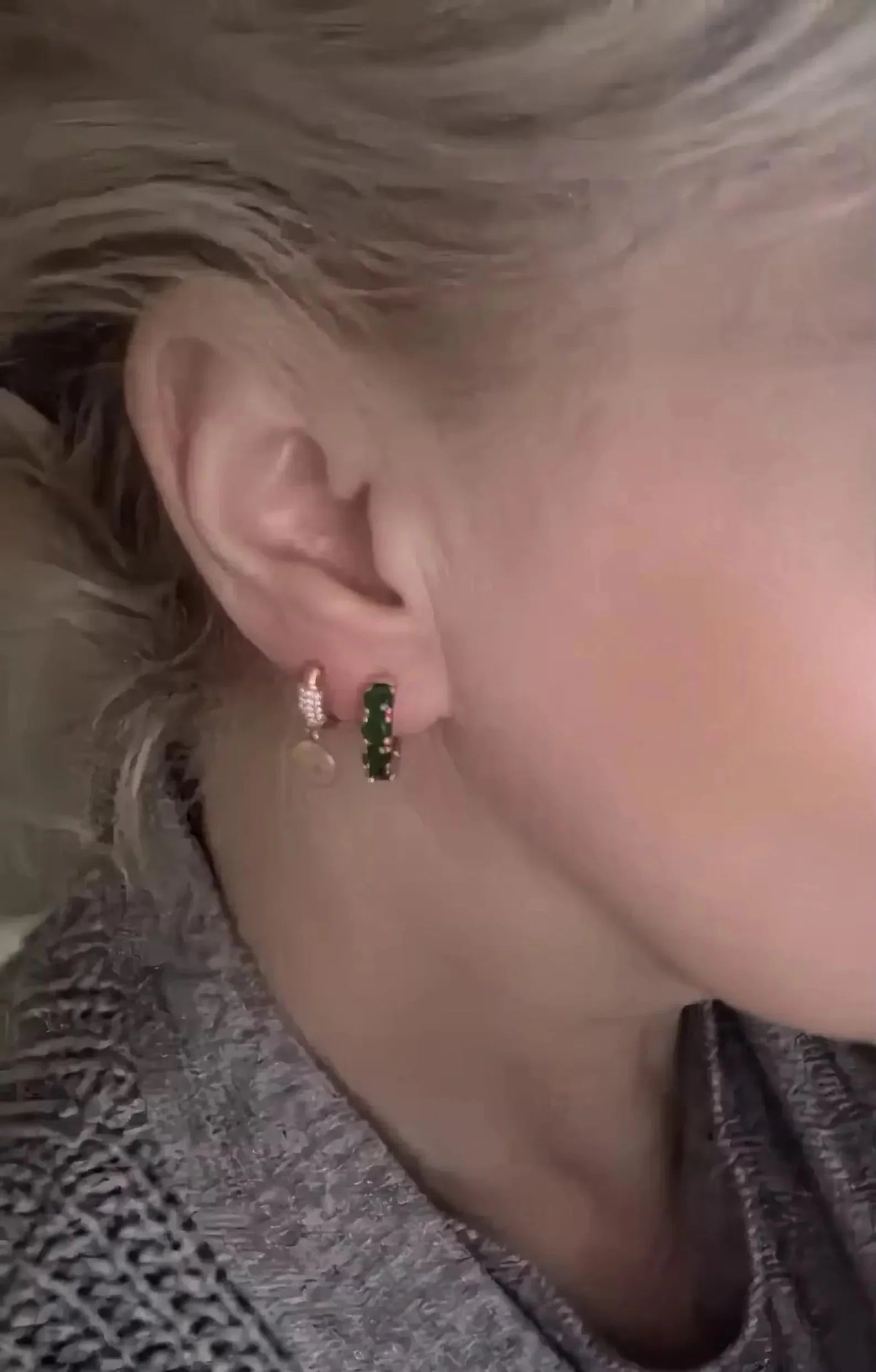 Dainty round-cut emerald hoop earring worn on an ear, showcasing its delicate size and vibrant color.