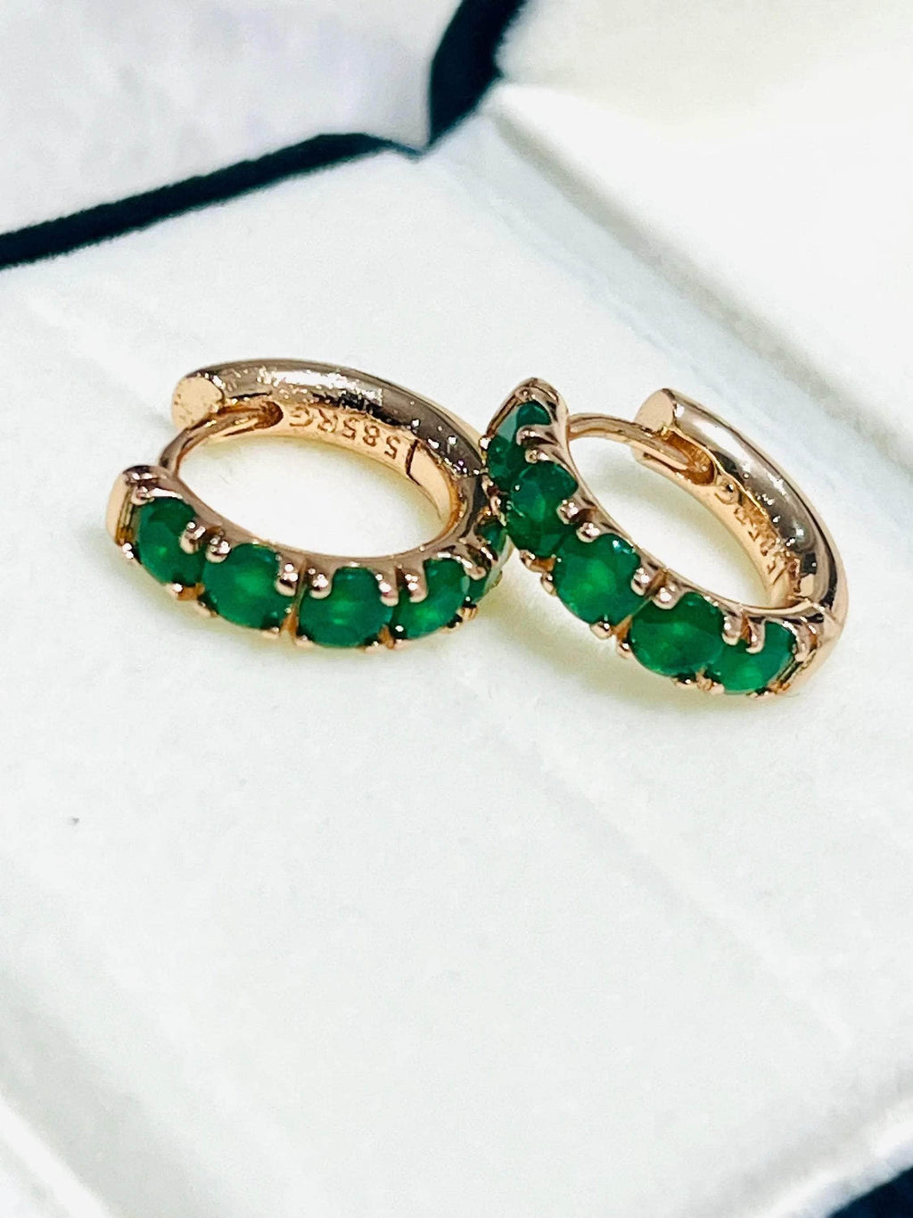 Set of elegant dainty round emerald hoop earrings in rose gold, showcasing their vibrant green gems.