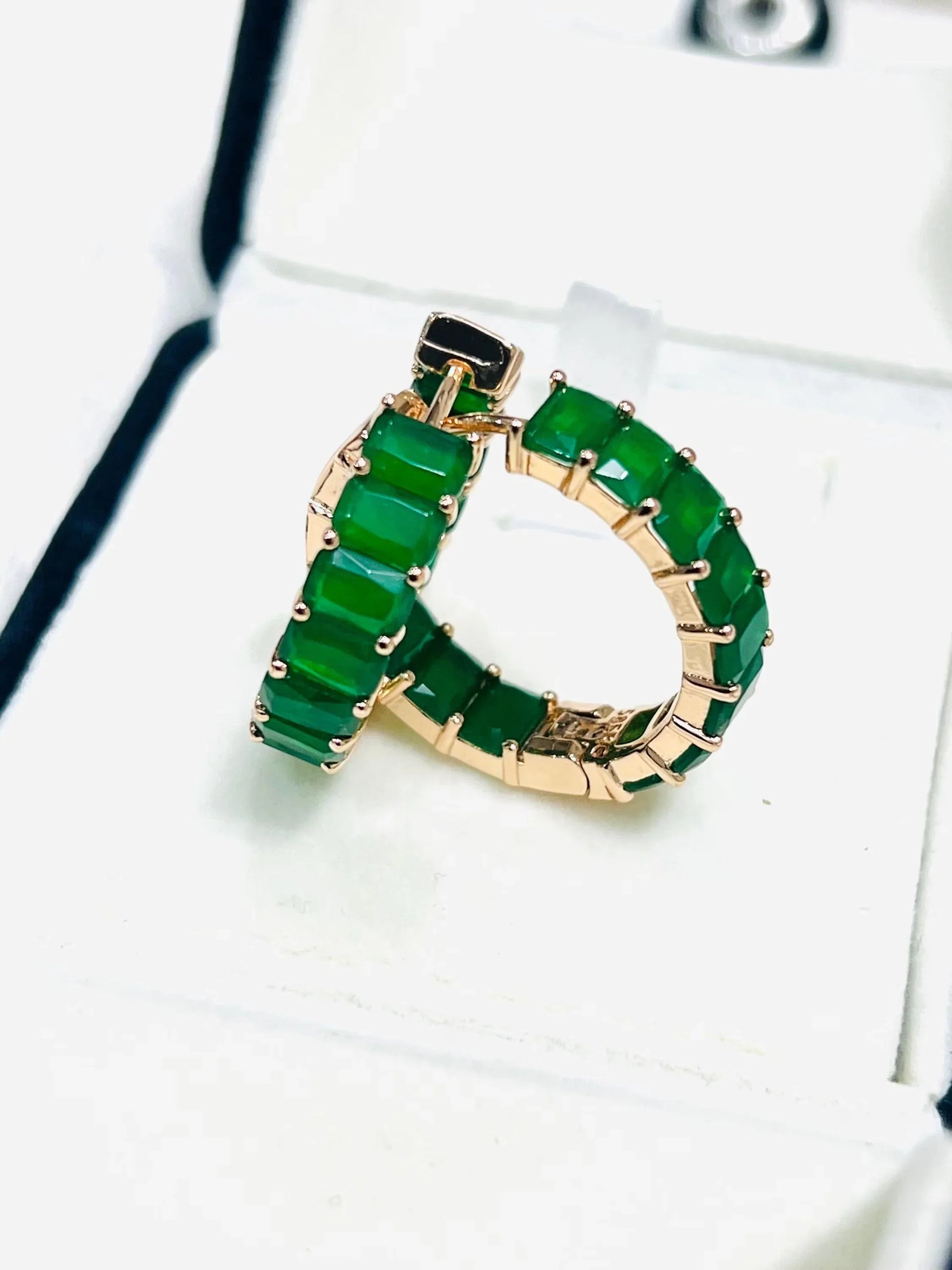 Close-up diagonal view of rose gold plated emerald matrix hoop earrings in a white box.