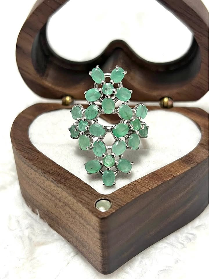  Top view of a dazzling sterling silver ring with natural Colombian emeralds arranged in a floral cluster design.