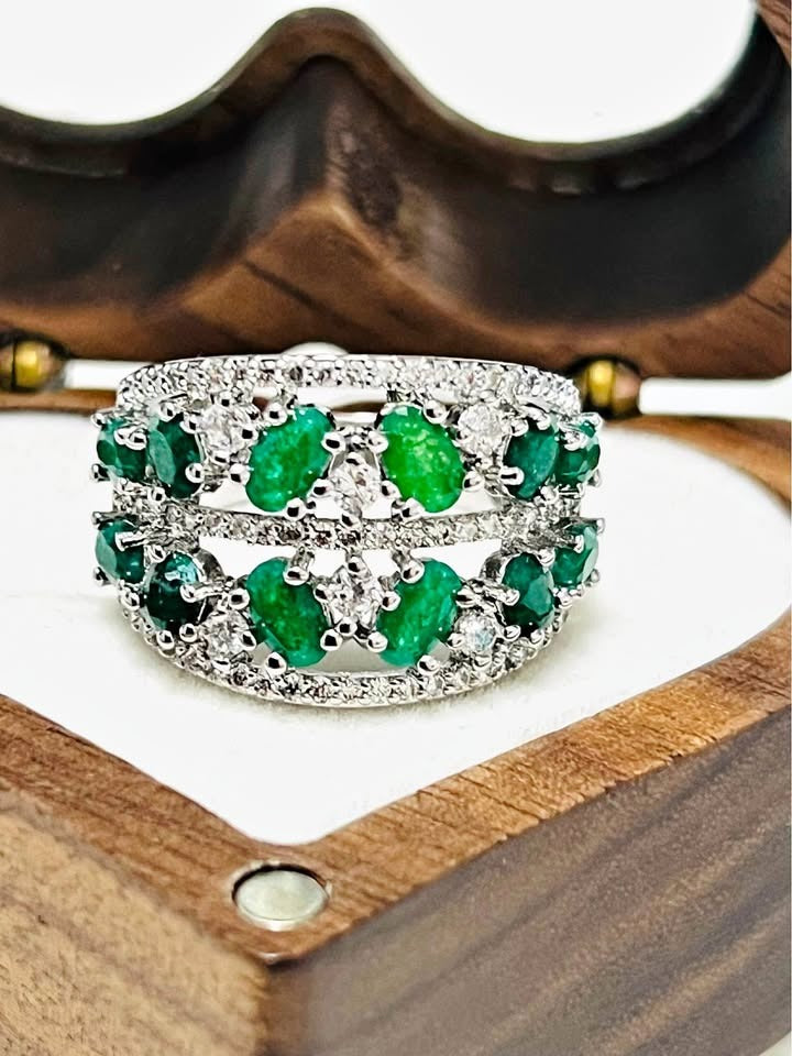 Close-up of a sterling silver ring set with numerous natural emeralds and sparkling white stones