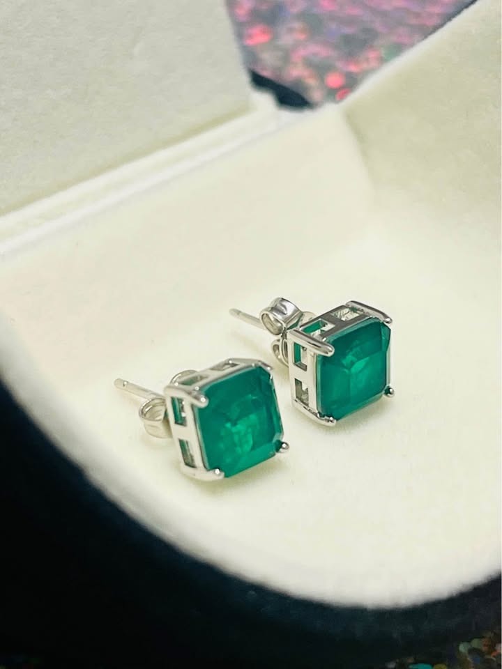Dainty genuine emerald square stud earrings in sterling silver, showcased at an angle in a white jewelry box.