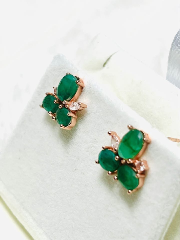  Side view of beautiful Colombian emerald stud earrings in a rose gold setting.