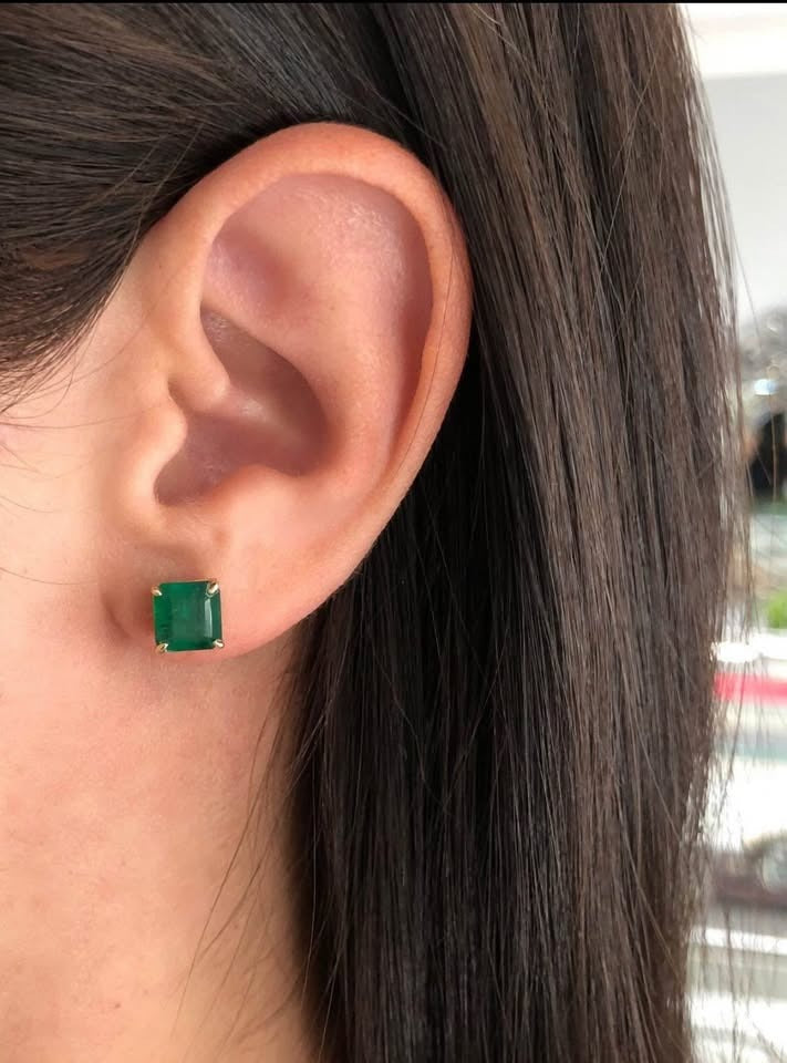  A woman wearing a dainty genuine emerald square stud earring in sterling silver, demonstrating its subtle elegance.