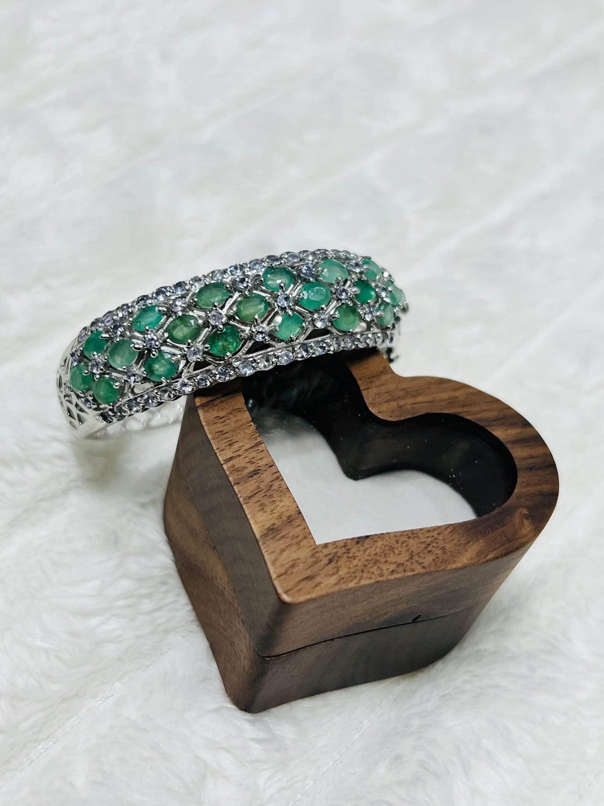 Aztec emerald and tanzanite bangle resting on an open heart-shaped wooden box, ready for gifting.
