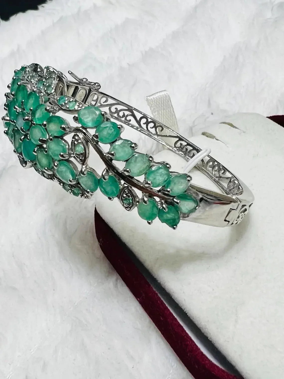 Side view of a stunning emerald and tanzanite floral bangle, showcasing intricate silver work and gemstones.