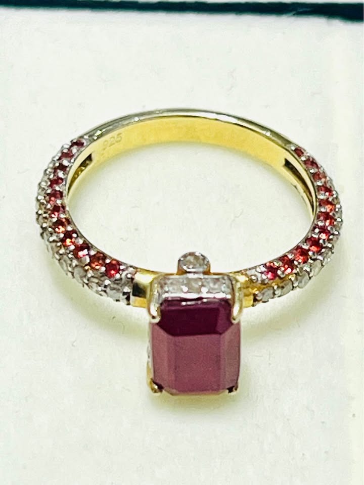 Close-up of an emerald cut natural ruby ring with diamond pave band.