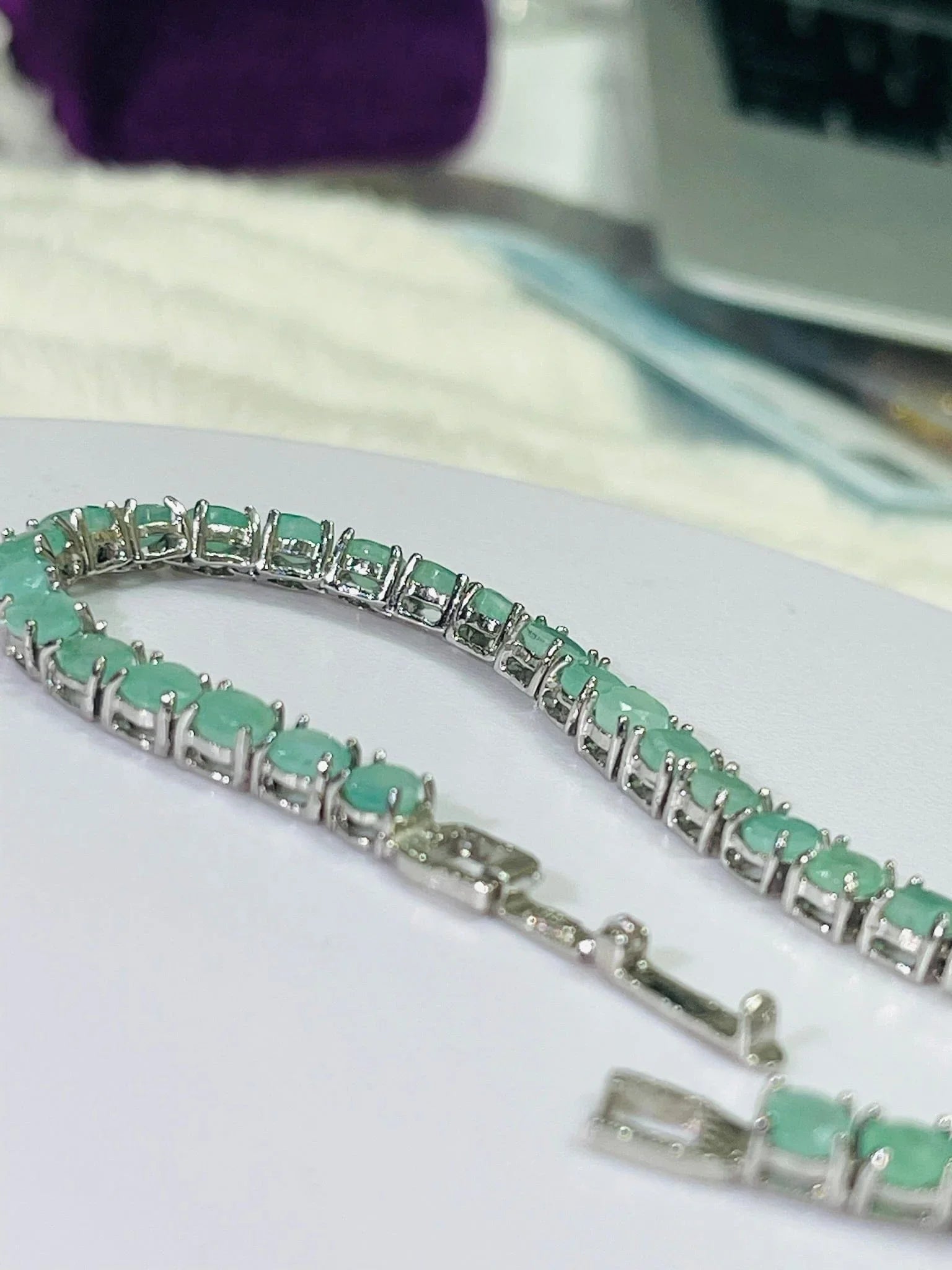 Silver emerald tennis bracelet with continuous line of round, vibrant green stones