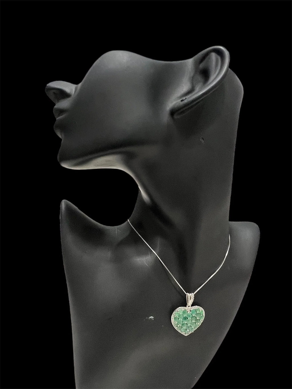 Side profile of a mannequin wearing the elegant sterling silver heart pendant, highlighting its natural Colombian emeralds.
