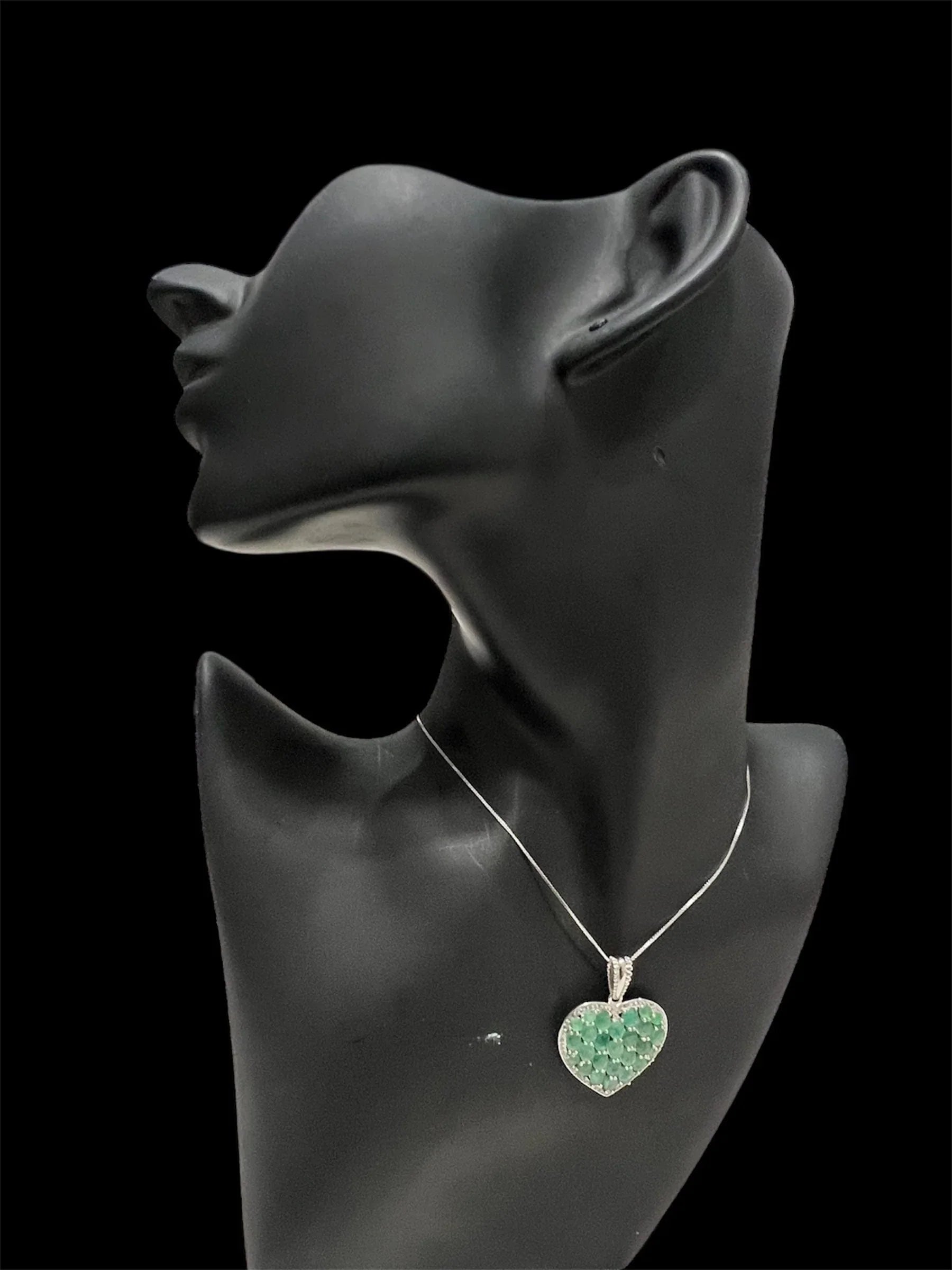Side profile of a mannequin wearing the elegant sterling silver heart pendant, highlighting its natural Colombian emeralds.