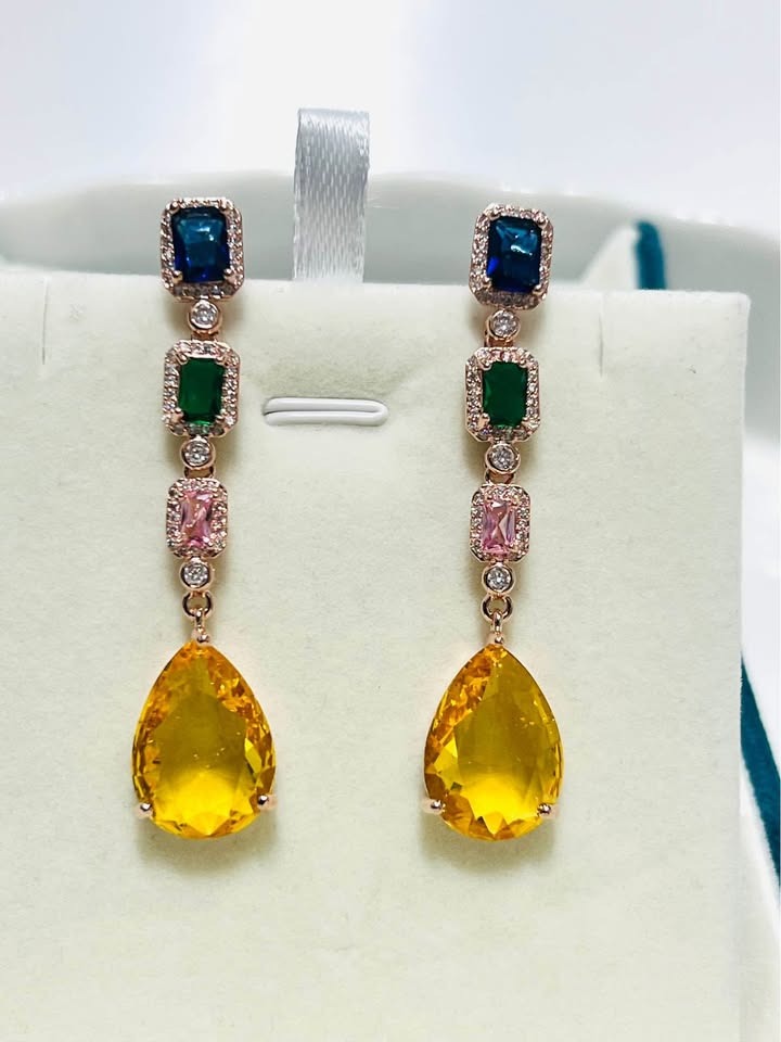 Elegant long dangle earrings featuring blue, green, pink, and yellow gems in a stylish, linear design.