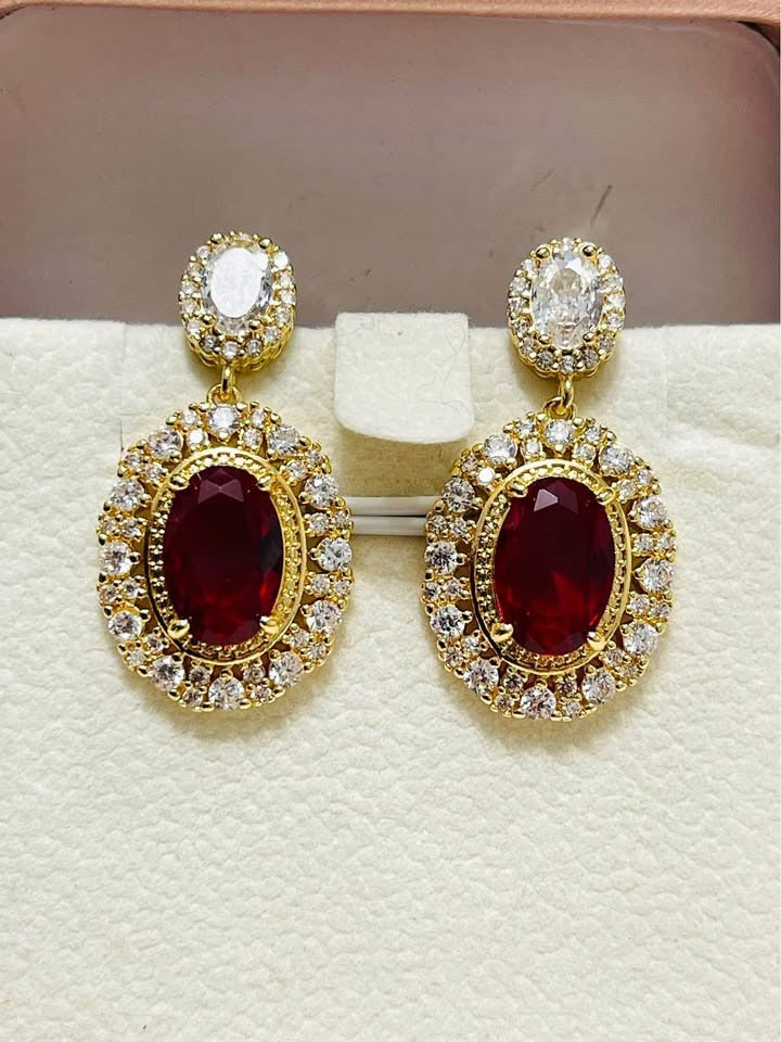 A top-down view of a pair of fancy gold-plated earrings, showcasing the graceful flow of the leaf and branch elements.