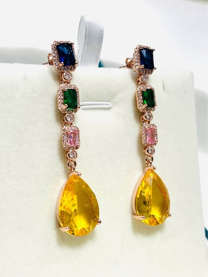 A pair of long dangle earrings featuring multi-colored gems in blue, green, pink, and yellow.
