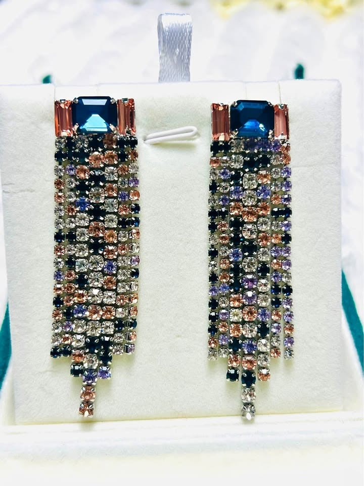  Fancy waterfall dangle earrings. The design includes a large blue gemstone and cascading strands of pink, purple, and clear gems.