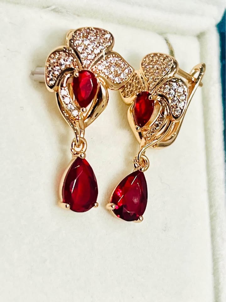 Detailed view of 14k 585RG stamped rose gold earrings with fancy red gemstones and clear pave accents.
