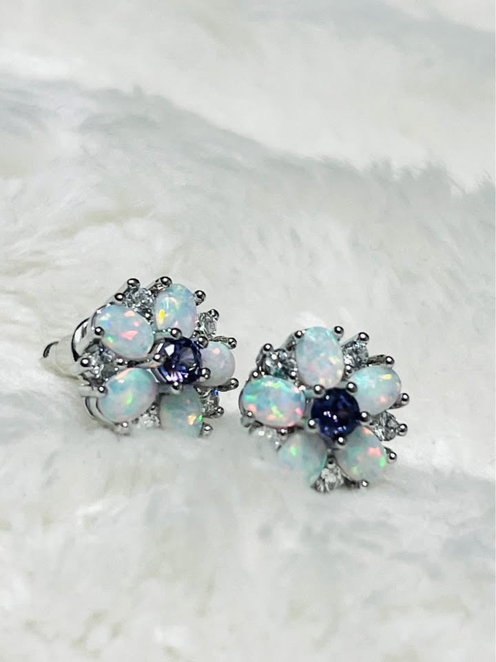 Elegant fire opal and amethyst flower stud earrings displayed on a soft, furry white background.