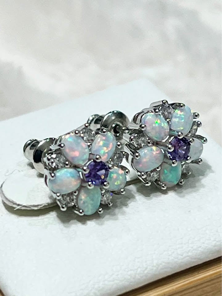 Angled view of delicate fire opal and amethyst flower stud earrings, highlighting their sterling silver setting.