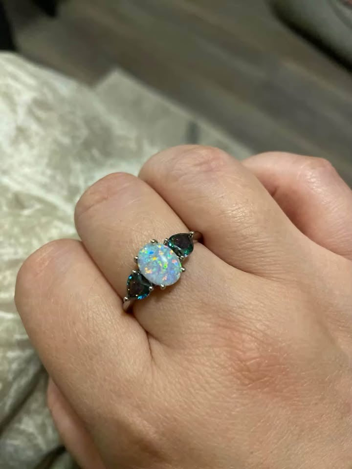 Hand showcasing a stunning 14K gold-plated ring with a center fire opal and two mystic topaz side stones.