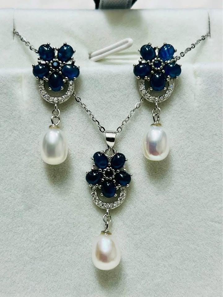Front view of a beautiful natural blue sapphire and pearl jewelry set including necklace and earrings.