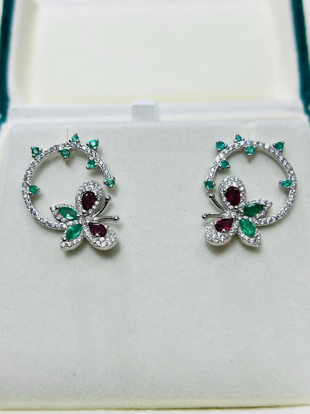 Exquisite gemstone butterfly and flower earrings with sparkling clear and green stones, in a white setting.